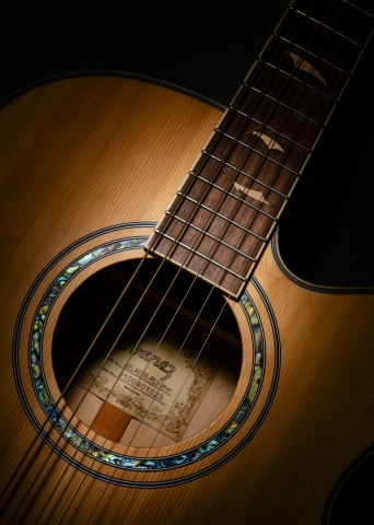 Dettaglio di chitarra acustica artigianale in luce drammatica