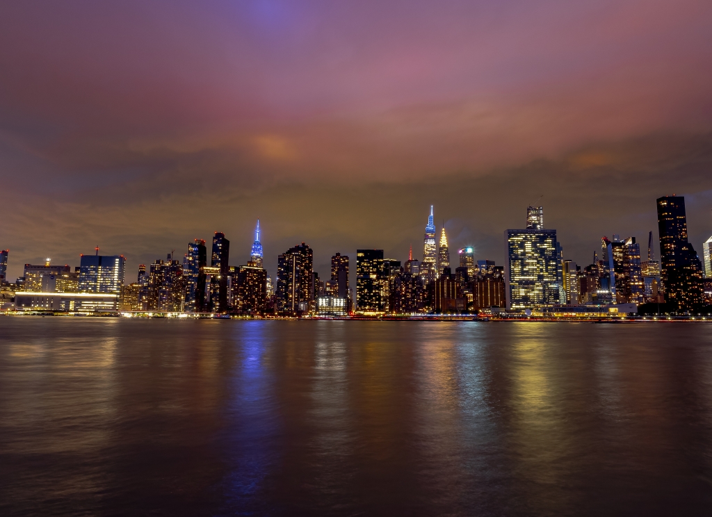 Skyline di New York di notte con riflessi sull’East River