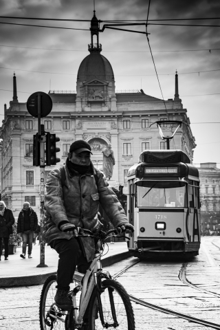 Milano in movimento: ciclista e tram storico in Piazza Cordusio