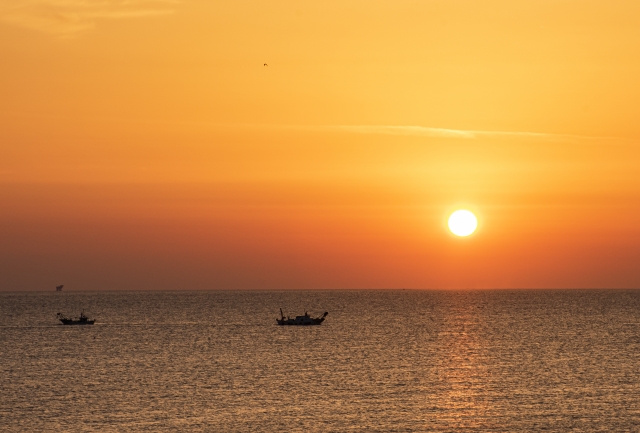 Alba dorata sul mare con barche di pescatori