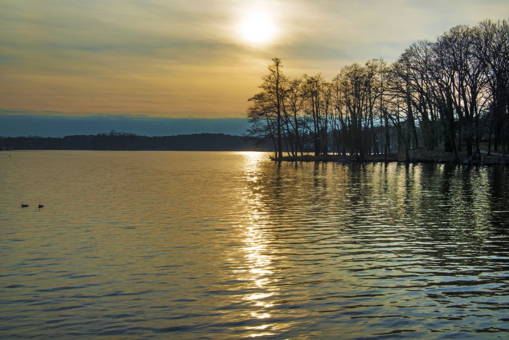 Paesaggio di lago con sole al tramonto.