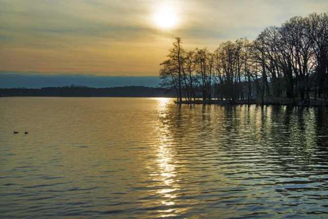 Paesaggio di lago con sole al tramonto.