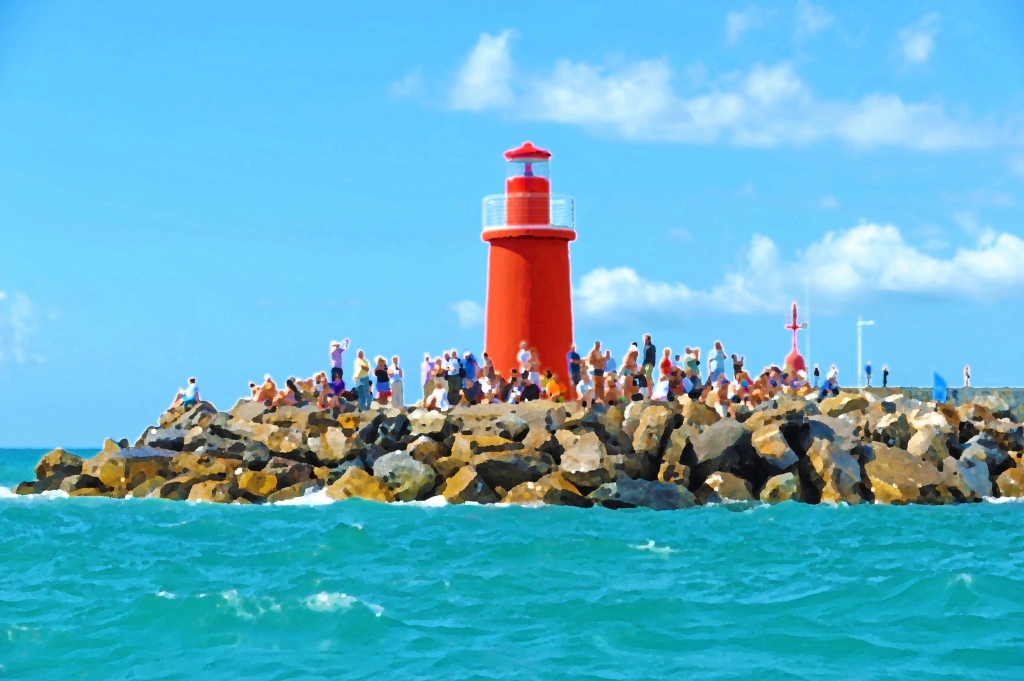 Folla sugli scogli all'ombra del faro.