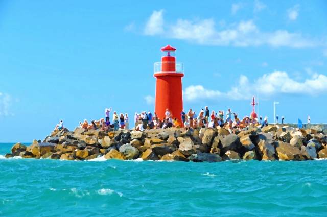 Folla sugli scogli all'ombra del faro.