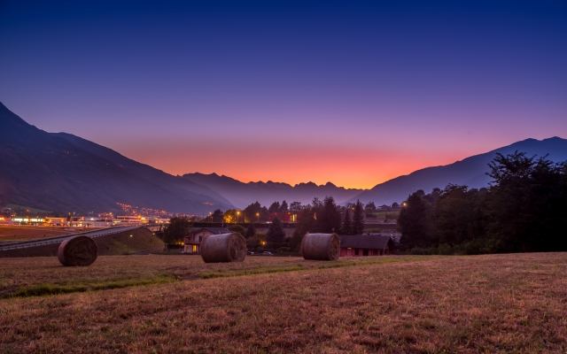 Rotoballe di fieno al tramonto con montagna di sfondo