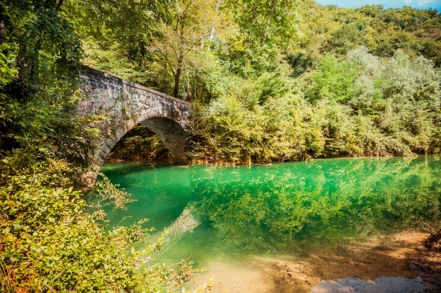 Ponte romano in mezzo al verde.