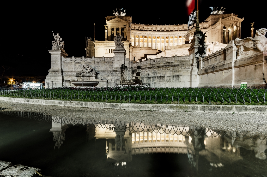 L'altare della Patria si riflette di notte in una pozzanghera