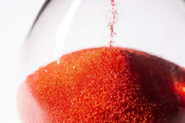 clessidra con sabbia rossa che cade, il tempo che scorre