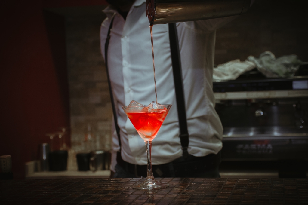 professional bartender prepares a cocktail in the martini glass