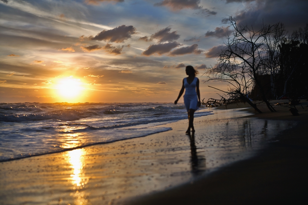 silouette di una ragazza sulla battigia all'alba