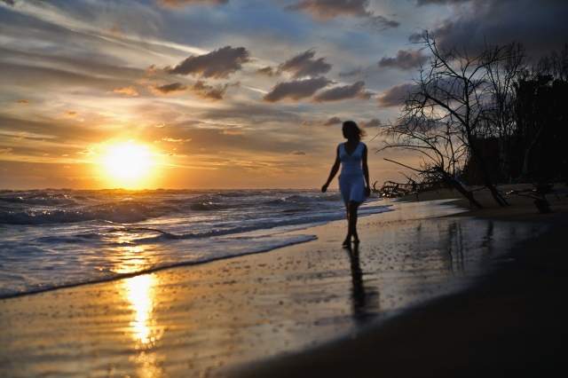 silouette di una ragazza sulla battigia all'alba