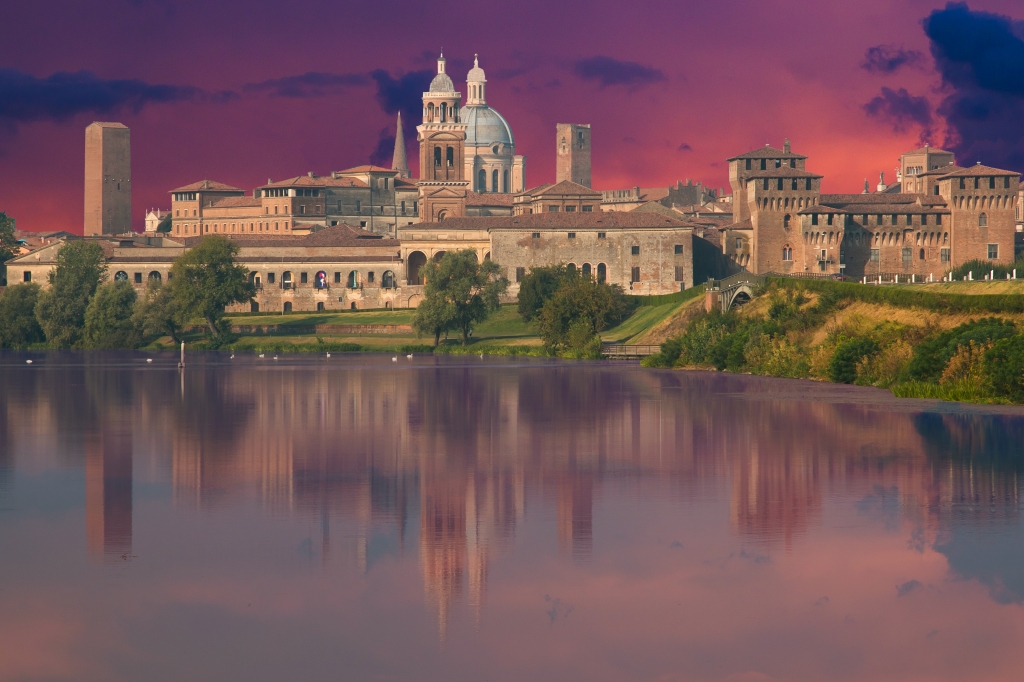Veduta panoramica di Mantova al tramonto riflessa sul Mincio